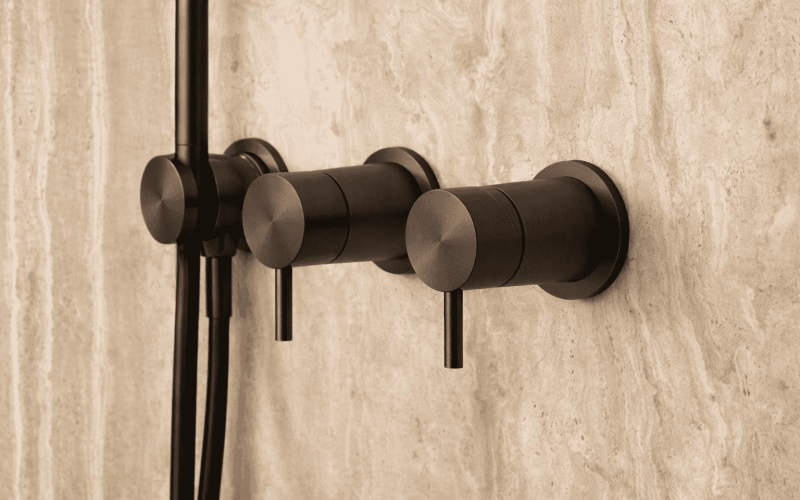 Zwarte badkamerkraan en handdouche op een beige tegelwand, modern en stijlvol design voor luxe badkamers.