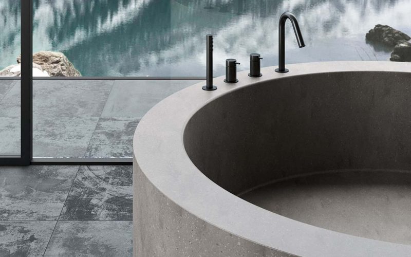 Luxe vrijstaande badkuip met moderne zwarte kranen en uitzicht op natuur, perfect voor een ontspannende badkamer met stijlvolle afwerking en hoogwaardige materialen.