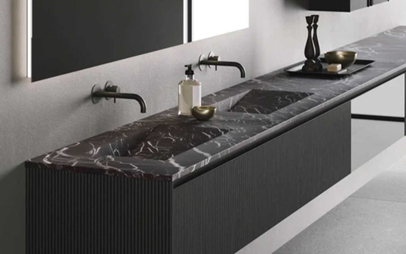 Zwarte badkamer wastafel met marmeren blad en dubbele kranen, modern en stijlvol design voor een luxe badkamerinterieur.
